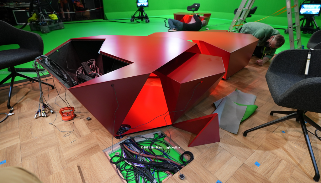 The Tokyo 2020 presenters desk partly diassanbled to allow cables, microsphhones and lights to be installed. Toby Kalitowski works on the desk.